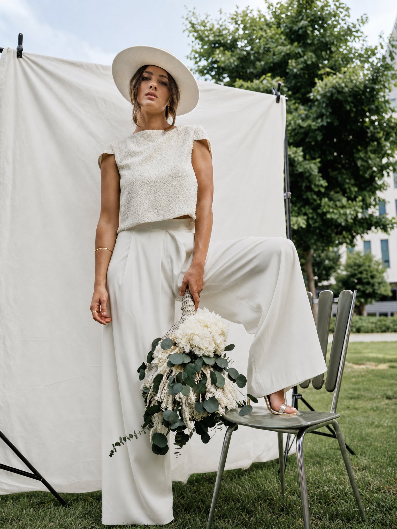 Mariée en tenue crème et chapeau blanc, tenant un bouquet cascade de fleurs séchées composé par Âme à Bordeaux | ÂME Fleuriste Bordeaux